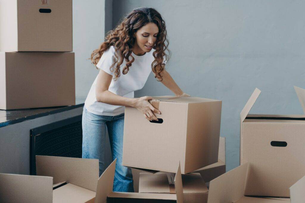 Female tenant packing things in boxes to move out from rented apartment. Moving, rental dwelling